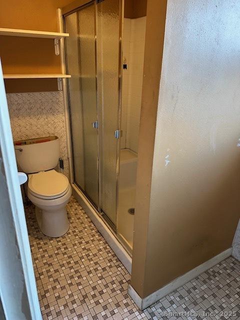 bathroom featuring tile patterned floors, toilet, and a shower with shower door