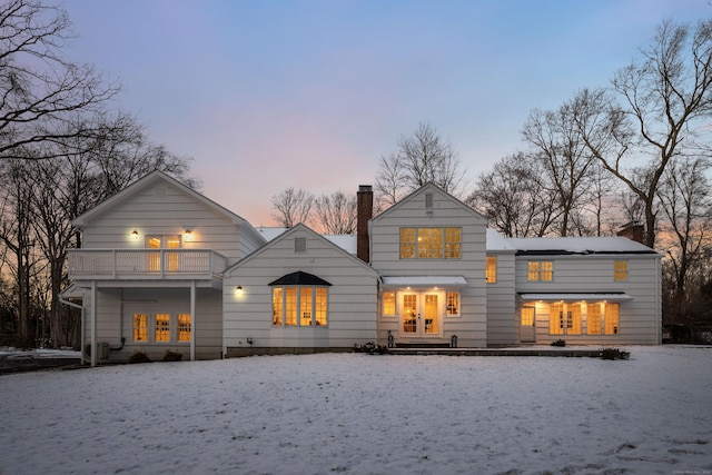 back house at dusk featuring a balcony