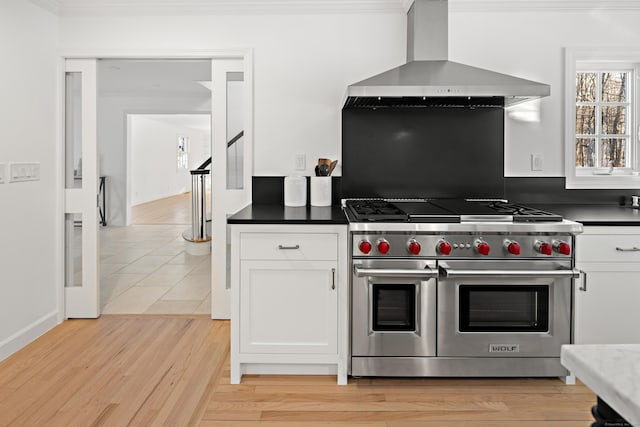 kitchen with white cabinetry, crown molding, double oven range, and wall chimney range hood