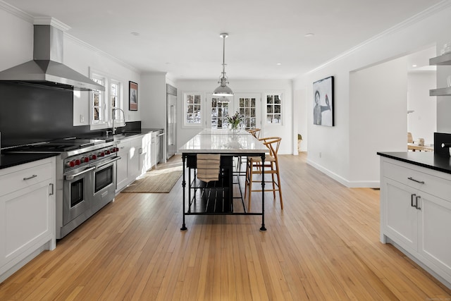 kitchen featuring white cabinets, wall chimney exhaust hood, high end appliances, and sink