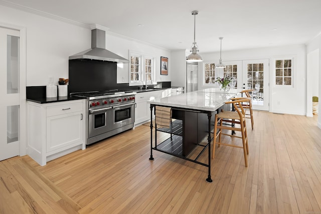 kitchen with french doors, wall chimney range hood, double oven range, light hardwood / wood-style floors, and white cabinetry