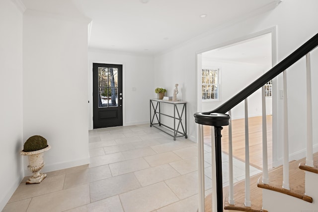 entrance foyer with a wealth of natural light, light tile patterned floors, and ornamental molding