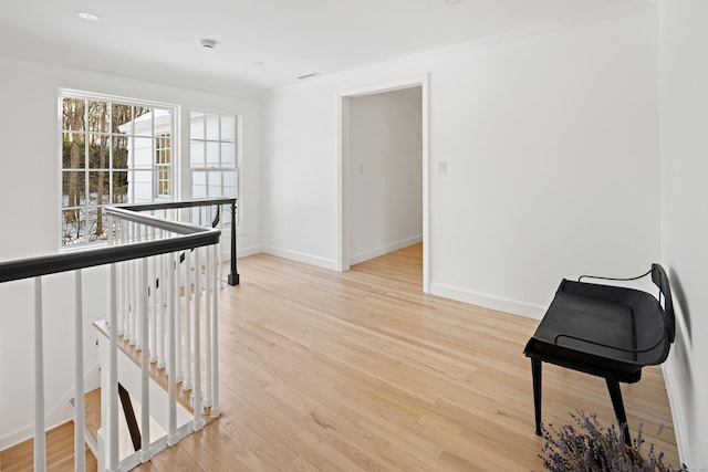 hall with light wood-type flooring and crown molding