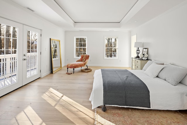 bedroom with light hardwood / wood-style floors, access to exterior, french doors, and a tray ceiling