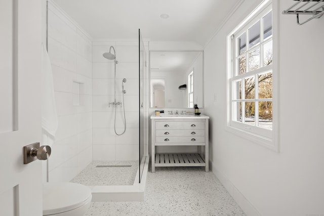 bathroom featuring a tile shower, a wealth of natural light, vanity, and toilet