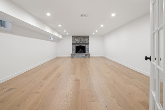 unfurnished living room featuring a stone fireplace and light hardwood / wood-style flooring