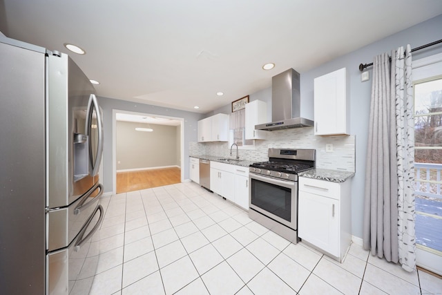 kitchen featuring white cabinetry, wall chimney range hood, sink, and appliances with stainless steel finishes