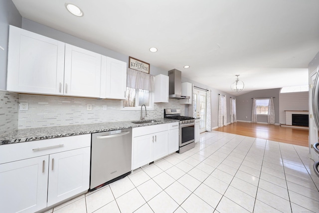 kitchen featuring white cabinets, sink, wall chimney exhaust hood, appliances with stainless steel finishes, and light stone counters