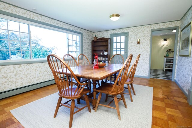 dining space with parquet flooring, a wealth of natural light, and a baseboard heating unit