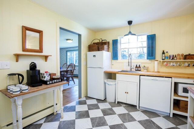 kitchen featuring white appliances, sink, hanging light fixtures, a healthy amount of sunlight, and white cabinetry