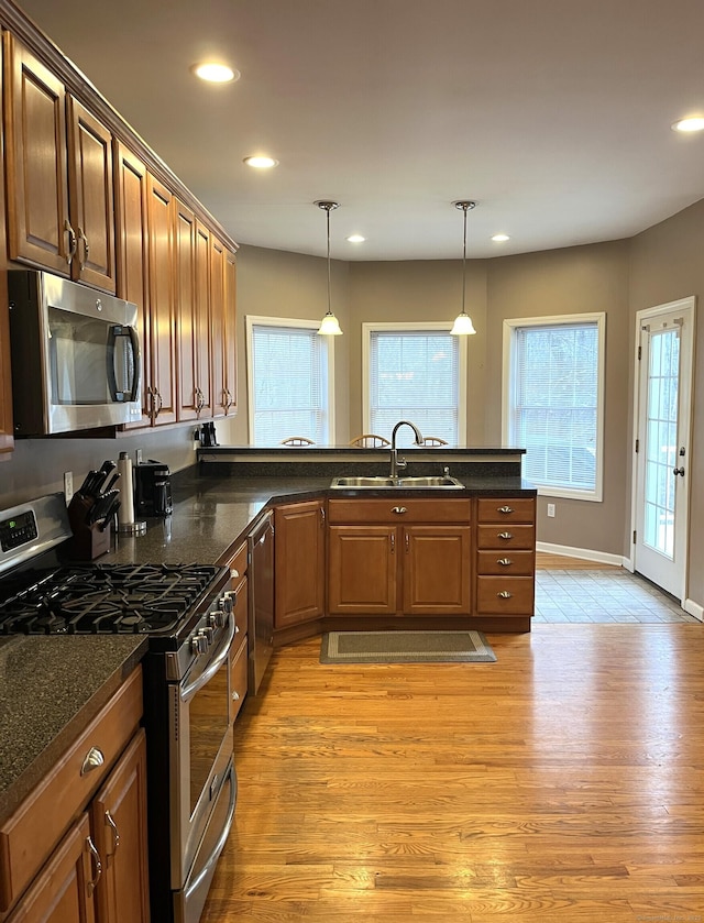 kitchen featuring pendant lighting, sink, appliances with stainless steel finishes, and light hardwood / wood-style flooring