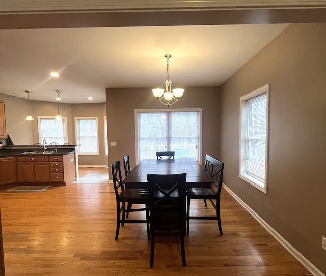 dining room with a chandelier, light wood-type flooring, and sink