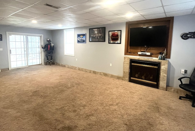 interior space featuring a tile fireplace, a drop ceiling, and carpet floors