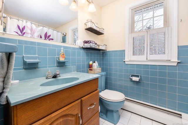 bathroom with baseboard heating, tile patterned flooring, vanity, tile walls, and toilet