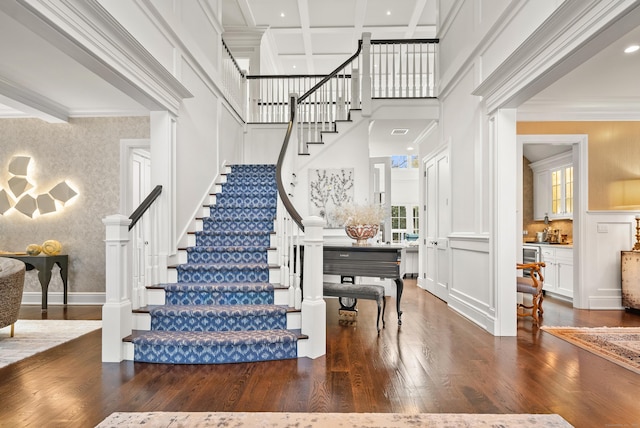 entrance foyer featuring coffered ceiling, a towering ceiling, dark wood-style flooring, beamed ceiling, and crown molding