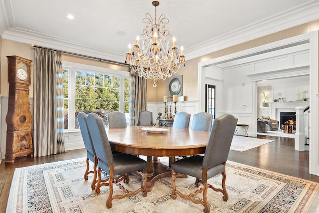 dining room featuring a decorative wall, dark wood-type flooring, a fireplace, wainscoting, and crown molding