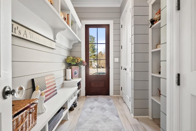 mudroom featuring wood walls, light wood-style flooring, and crown molding