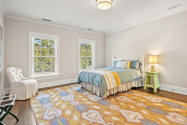 bedroom with baseboards, crown molding, visible vents, and wood finished floors