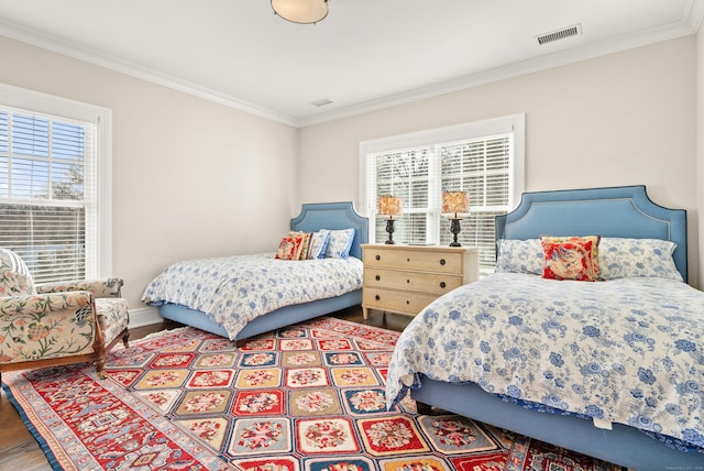 bedroom featuring visible vents, crown molding, baseboards, and wood finished floors