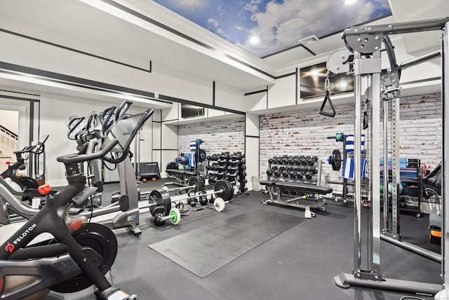 exercise room featuring brick wall, visible vents, and crown molding