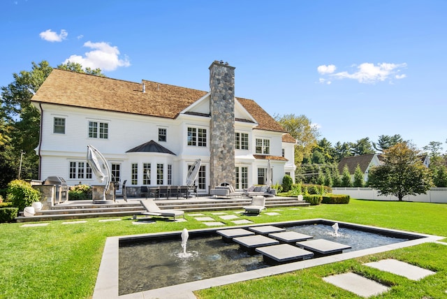 back of house featuring a lawn, a patio, a chimney, fence, and french doors