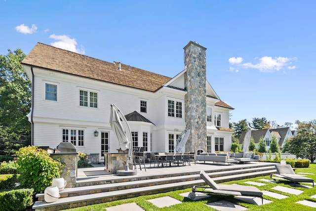 rear view of house featuring a chimney, an outdoor living space, exterior kitchen, and a patio