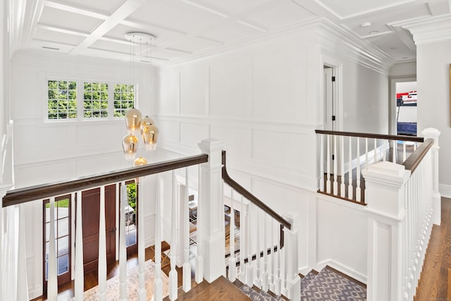 stairs featuring crown molding, coffered ceiling, a decorative wall, and wood finished floors