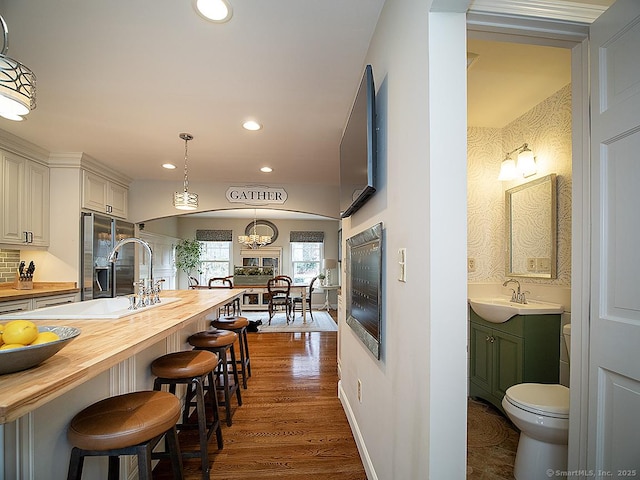 kitchen with white cabinetry, sink, dark hardwood / wood-style floors, butcher block countertops, and pendant lighting