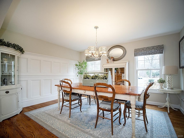 dining space featuring dark wood-type flooring and an inviting chandelier