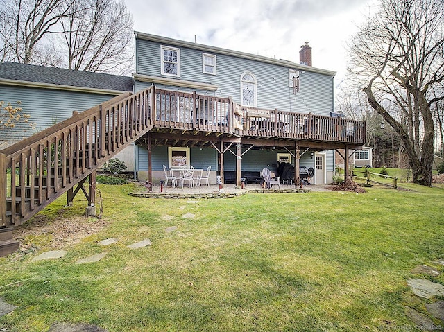 rear view of house featuring a lawn, a wooden deck, and a patio area