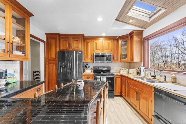 kitchen with sink, tasteful backsplash, dark stone counters, and black appliances