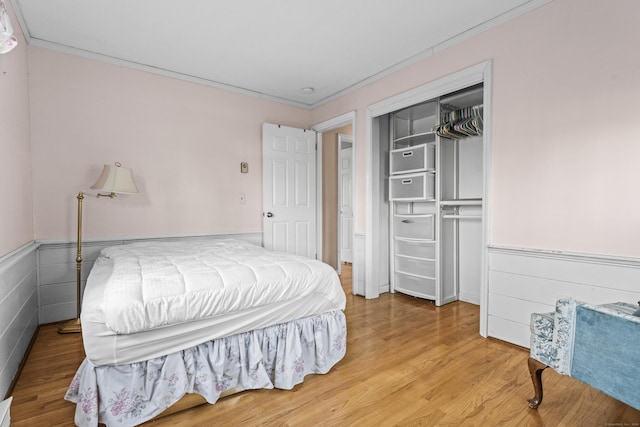 bedroom with wood-type flooring, a closet, and ornamental molding