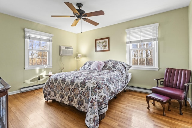 bedroom featuring baseboard heating, ceiling fan, multiple windows, and a wall mounted air conditioner