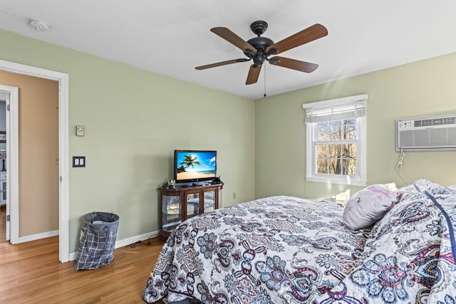 bedroom featuring ceiling fan, light hardwood / wood-style flooring, and a wall mounted air conditioner