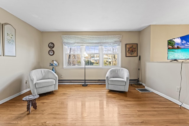 sitting room featuring a baseboard heating unit and light hardwood / wood-style flooring