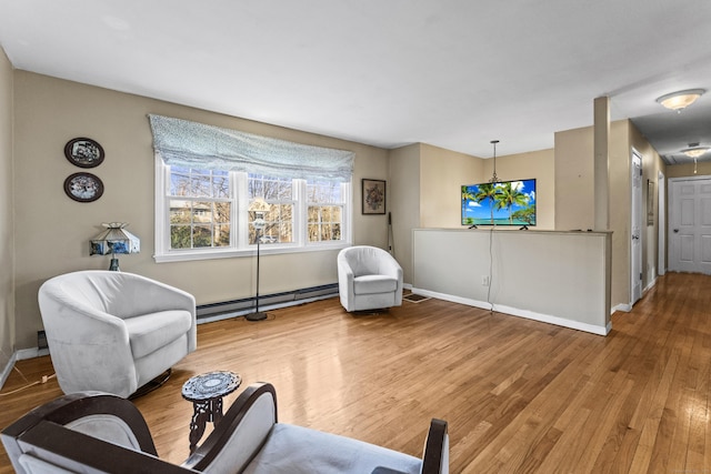 sitting room featuring wood-type flooring, a notable chandelier, and a baseboard radiator