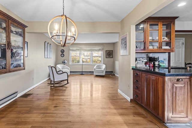 living area with a notable chandelier, a baseboard radiator, and light hardwood / wood-style floors