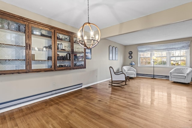 unfurnished room with an inviting chandelier, hardwood / wood-style flooring, and a baseboard radiator