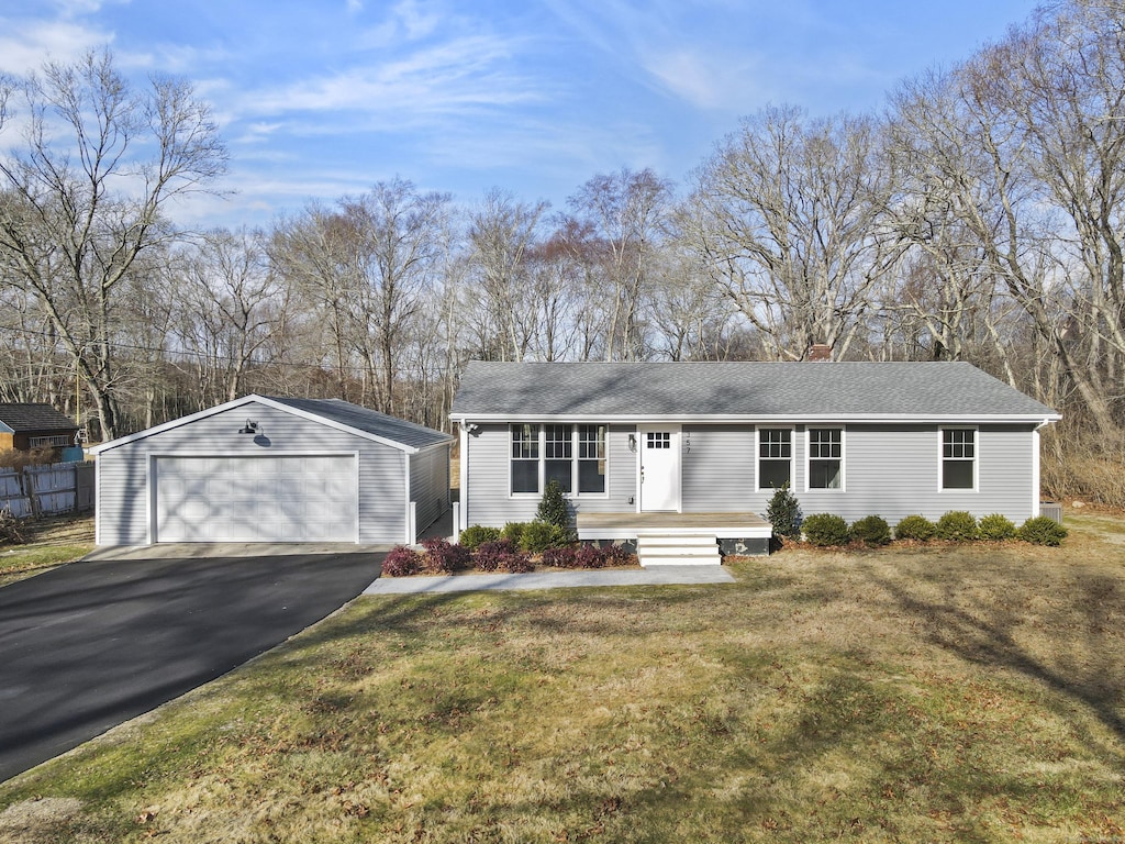 ranch-style house with a garage, a front yard, and an outbuilding