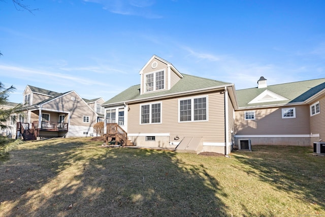 back of property with central AC unit and a yard