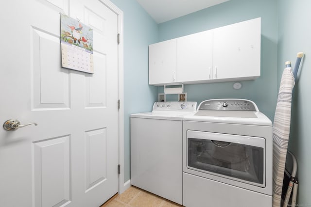 laundry area with washing machine and dryer, light tile patterned flooring, and cabinets