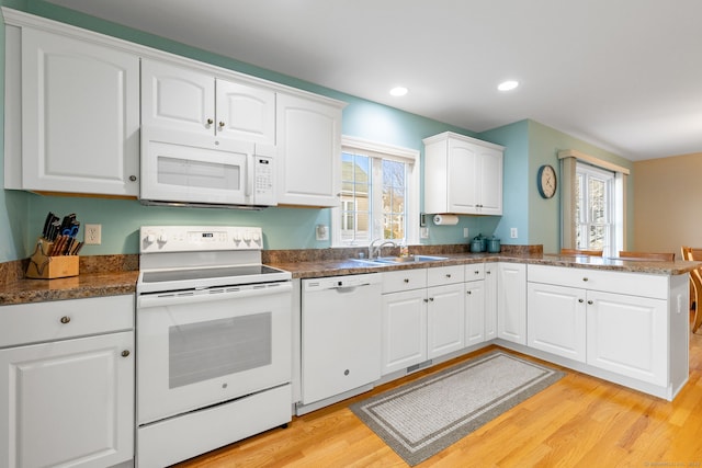 kitchen featuring white appliances, white cabinets, sink, light hardwood / wood-style flooring, and kitchen peninsula