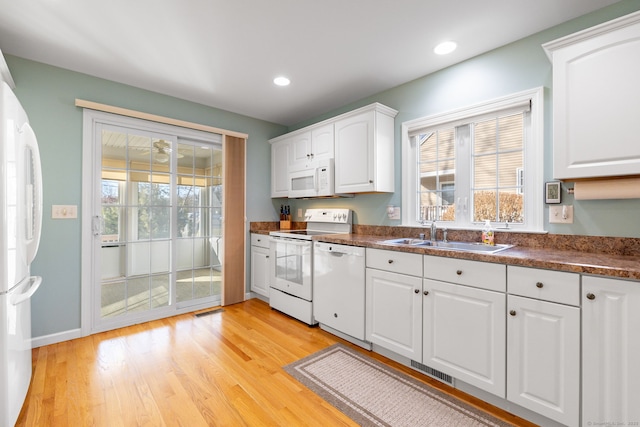 kitchen with white cabinetry, white appliances, sink, and light hardwood / wood-style flooring