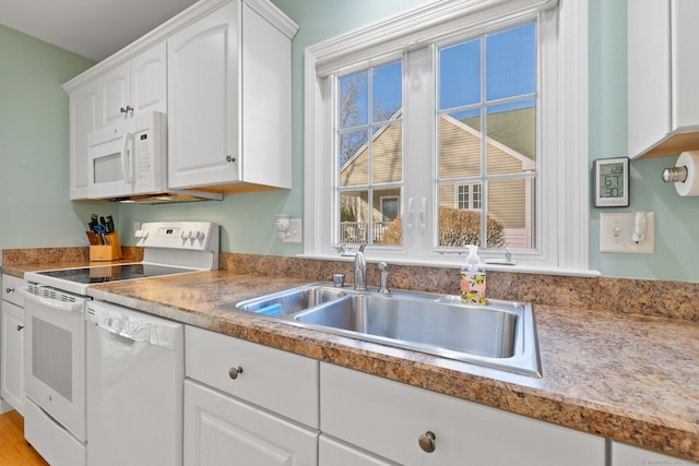 kitchen with white cabinetry, sink, white appliances, and light hardwood / wood-style flooring