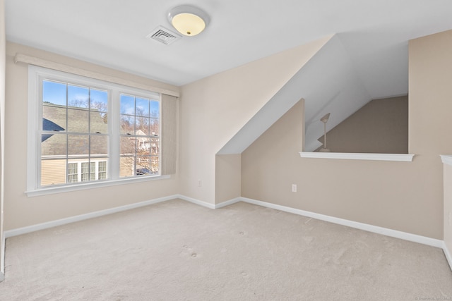 additional living space with light colored carpet and vaulted ceiling