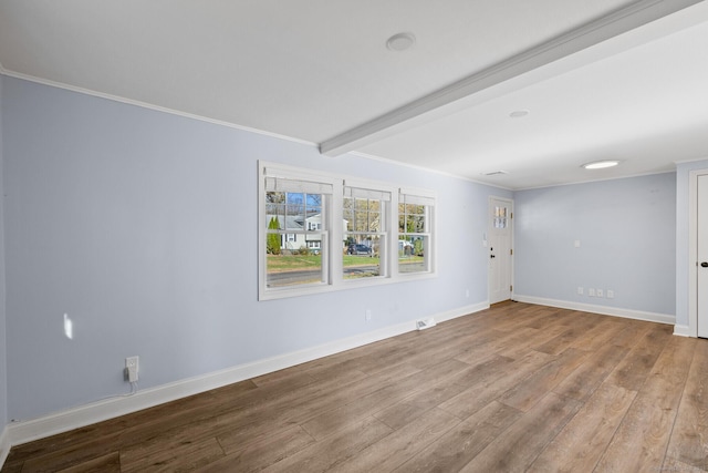 empty room featuring ornamental molding, light wood-type flooring, and beamed ceiling