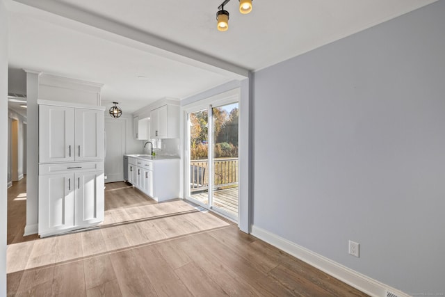 interior space featuring white cabinets, light hardwood / wood-style flooring, and sink