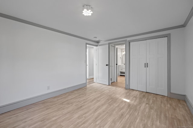 unfurnished bedroom with ornamental molding, light hardwood / wood-style flooring, and a closet