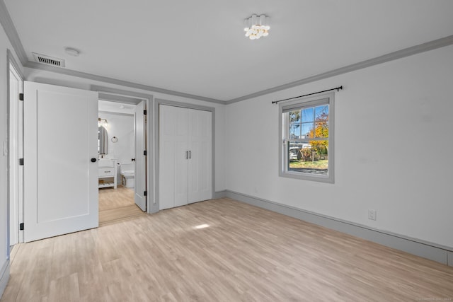 unfurnished bedroom featuring ensuite bath, a closet, light wood-type flooring, and crown molding