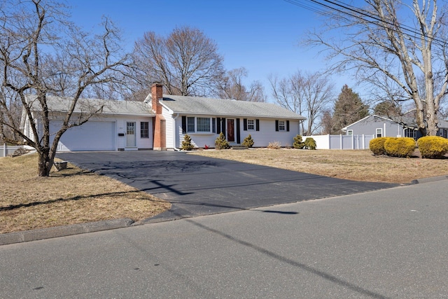 ranch-style house with an attached garage, fence, driveway, and a chimney